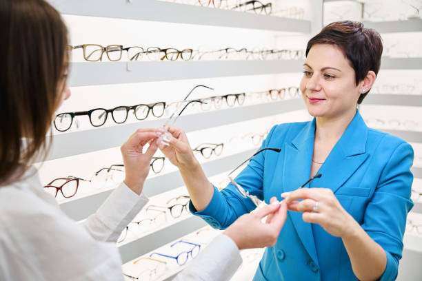 Pleased female client taking two pairs of rimless spectacles from optician hands