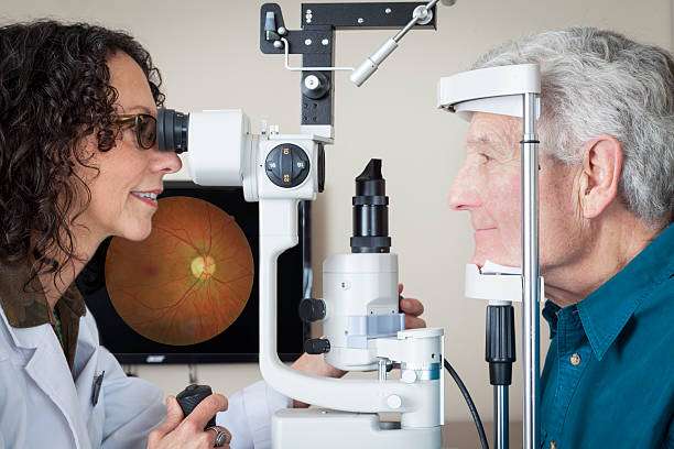 Optometrist giving eye exam to senior patient