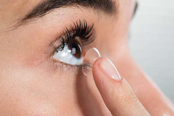 Closeup of young woman wearing contact lens at home